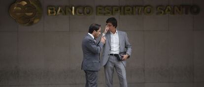 Dos hombres charlan junto a la fachada del Banco Esp&iacute;rito Santo en Lisboa.