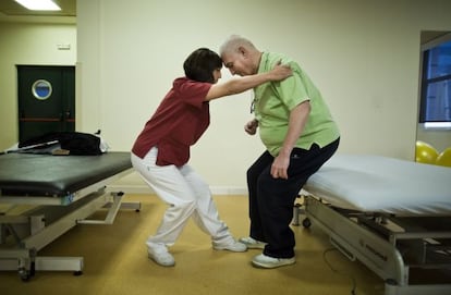 Marta Fernández, fisioterapeuta, ayuda a Javier Herreros a realizar unos ejercicios en el Centro Estatal de Atención al Daño Cerebral, en Madrid.