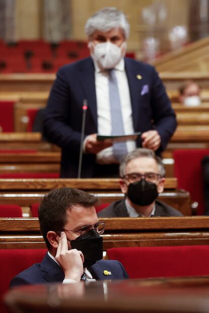 En primer plano, el 'president' Pere Aragonès, escucha al portavoz de JxCat, Albert Batet (fondo), durante el pleno del Parlament.