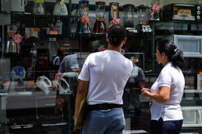 Dos transeúntes observan el escaparate de una tienda de electrodomésticos en Caracas.