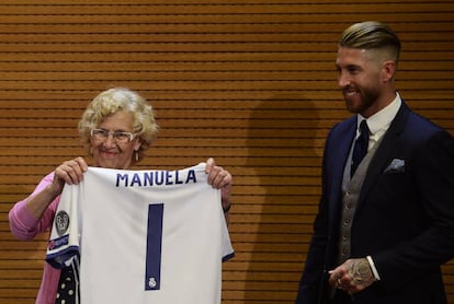 La alcaldesa de Madrid, Manuela Carmena, sujeta la camiseta del Real Madrid junto al capitán del equipo blanco, Sergio Ramos, en Cibeles.
