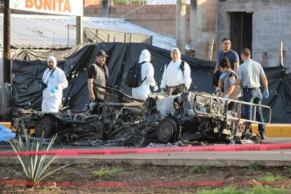 Forenses junto a una de las patrullas calcinadas en Culiac&aacute;n