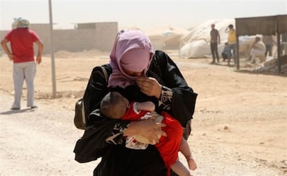Una mujer siria camina junto a su hijo en el campo de refugiados de Zaatari, en Jordania.