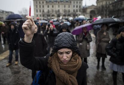 Una mujer alza simbólicamente un lapicero mientras guarda un minuto de silencio ante la catedral de Notre Dame de París, el 8 de enero de 2015, en memoria de las doce víctimas del atentado contra las oficinas de la publicación 'Charlie Hebdo'.