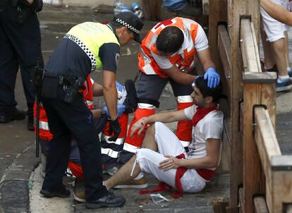 El peligro ha vuelto en los primeros metros de la calle Estafeta, donde varios toros han alcanzado a algunos mozos, pero sin llegar a embestirles, aunque uno de ellos ha quedado con la espalda encajada entre las astas de un toro negro, hueco que le ha evitado la cornada. En la imagen, personal de emergencias atiende a un corredor herido durante el encierro.