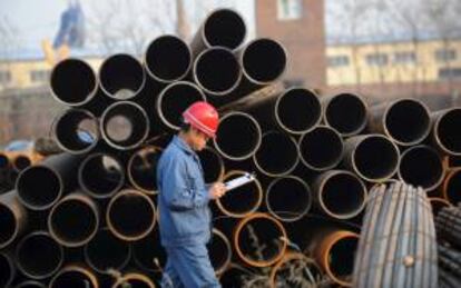 Un trabajador pasa junto a varias tuberías de acero en un almacén en Shenyang, noreste de China.