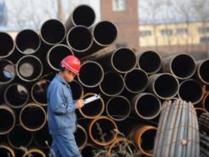 Un trabajador pasa junto a varias tuberías de acero en un almacén en Shenyang, noreste de China.