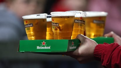 Un consumidor carga una bandeja con varias cervezas Heineken.