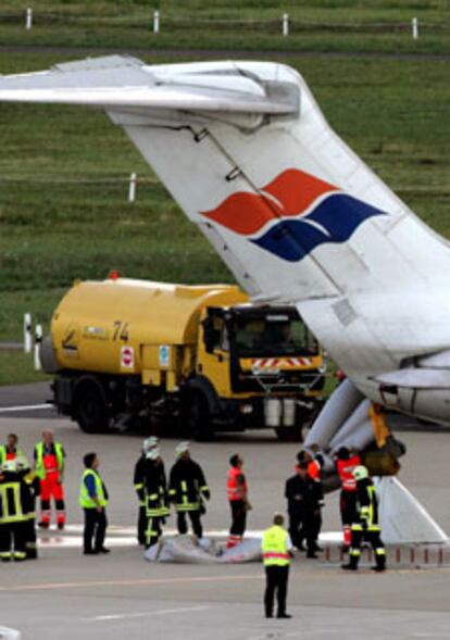 Una dotación de bomberos del aeropuerto de Colonia recoge uno de los toboganes de emergencia del aparato.