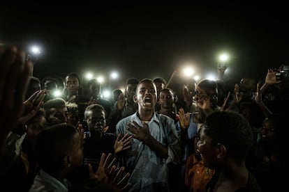 Un jove, illuminat per mbils, recita un poema mentre els manifestants canten consignes demanant un govern civil, durant un tall de llum a Khartum (Sudan), el 19 de juny del 2019.