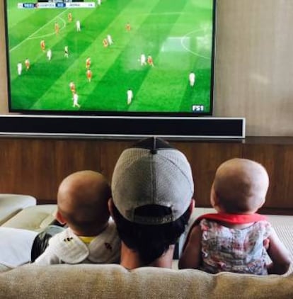 Enrique Iglesias con sus dos niños siguen atentos un partido de fútbol.
