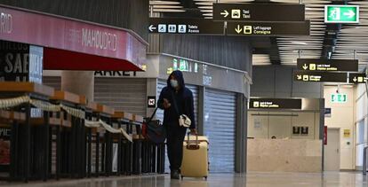  Un pasajero camina por el aeropuerto de Barajas entre tiendas y bares cerrados. 