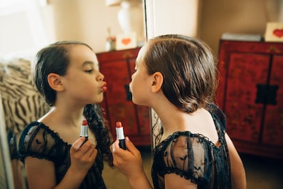 Mixed race girl applying lipstick in mirror