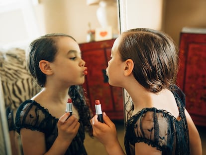 Mixed race girl applying lipstick in mirror