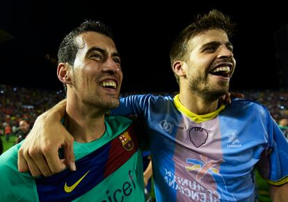 Busquets y Piqué, con una camiseta del Levante puesta al revés, sonríen tras proclamarse campeones de Liga.