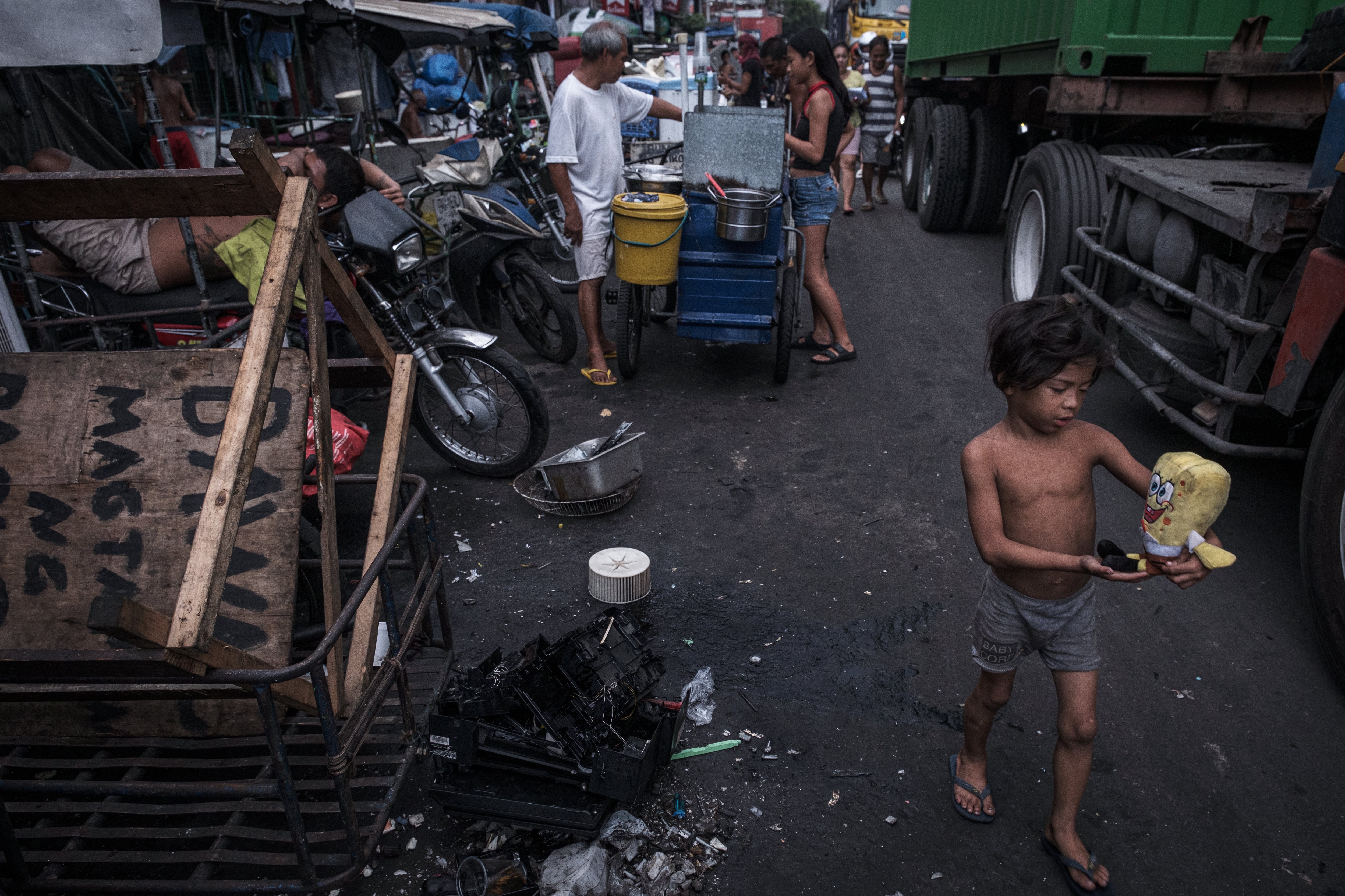 Un niño camina entre un camión y restos de chatarra electrónica que están siendo reciclados, en Tondo, Metro Manila.