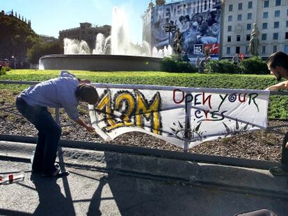 Dos simpatizantes del movimiento 15M ponen una pancarta en la plaza de Catalunya.