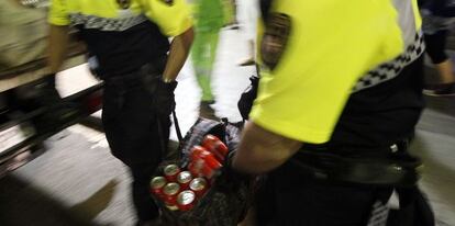 Agentes de la Guardia Urbana de Barcelona cargan con latas intervenidas en La Rambla. 