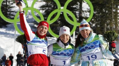 La noruega Marit Bjoergen, ganadora del oro, flanqueada por la polaca Justyna Kowalczyk, plata y la eslovena Petra Majdic, bronce.