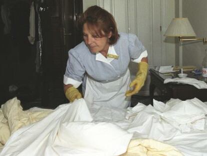 Una camarera hace la cama en un hotel.