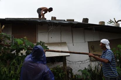 Tres residentes refuerzan el techo de sus hogares, en la ciudad de Tuguegarao (Filipinas).