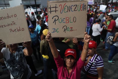 Simpatizantes del chavismo muestran carteles de apoyo al Gobierno de Maduro.