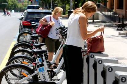 Dos mujeres sacan una bicicleta pública de una base de Bicimad.