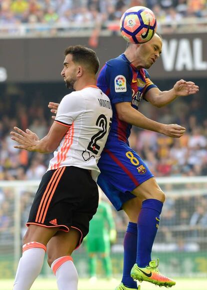 Martín Montoya (i) del Valencia CF y Andrés Iniesta del FC Barcelona saltan para golpear de cabeza.