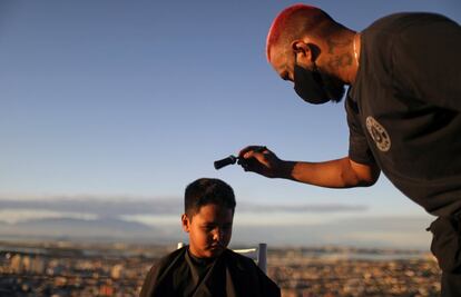 El peluquero Renan Estate le corta el pelo a un niño en su casa como parte de su servicio de "peluquero de reparto", ya que su local está cerrado debido al coronavirus, en la favela del Complexo do Alemao, en Río de Janeiro (Brasil).