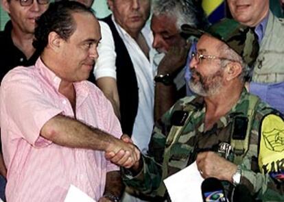 El negociador de las FARC, Raúl Reyes, y al alto comisionado para la paz, Camilo Gomez, chocan la mano tras firmar el documento.