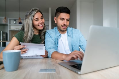 Feliz pareja en casa organizando sus finanzas y pagando facturas.