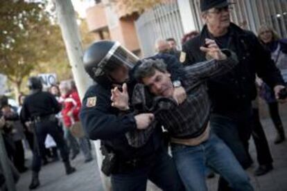 Efectivos de la policía detienen a uno de los asistentes a la concentración llevada a cabo ante la Asamblea de Madrid.