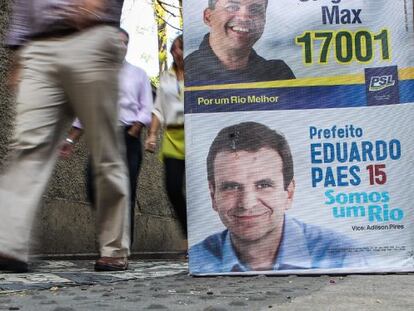 Transeúntes cerca de un afiche publicitario de la campaña del alcalde de Río de Janeiro.