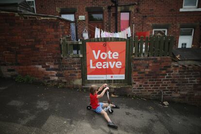 Una joven con patinete pasa delante de un cartel a favor del Brexit, en Batley (Inglaterra), el 16 de junio de 2016.