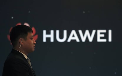 Logo de Huawei en un stand de la compa&ntilde;&iacute;a junto a una persona de seguridad. 