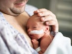 Un padre cuida de su bebé prematuro haciendo piel a la piel en el hospital.