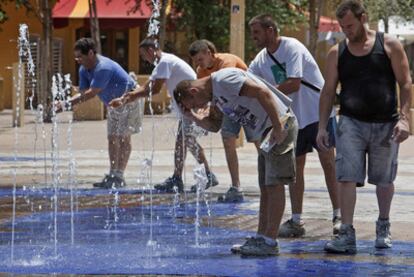 Unas personas se refrescan por el calor en una fuente céntrica de Sevilla, una de las tres provincias andaluzas que se encuentra en alerta amarilla por las altas temperaturas.