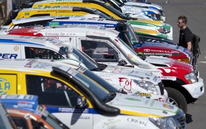 Un hombre observa algunos de los coches del Dakar.