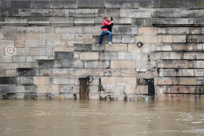 Una pareja de jóvenes se besa en unas escaleras a la orilla del río Sena en París, Francia.