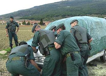 Guardias civiles cubren la furgoneta desde la que ayer fue lanzada una granada contra un cuartel, al fondo.