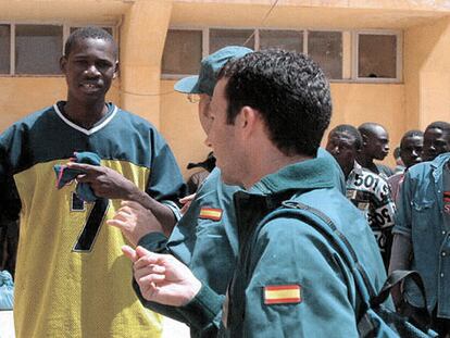 Guardias civiles conversan con un subsahariano en el cuartel de la Gendarmería marroquí en El Aaiún.