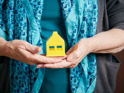 Senior woman's hands hold little toy house