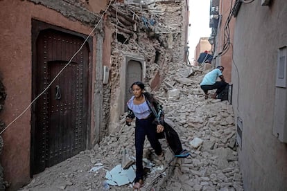 Una mujer camina entre los escombros de varios edificios en una calle de Marraquech.
