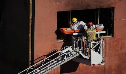 Los bomberos retiran el cuerpo de una de las víctimas.