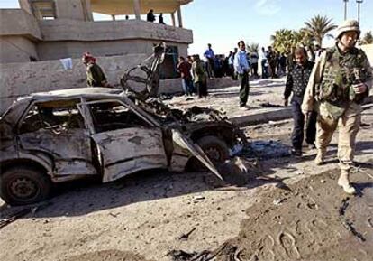 Un oficial estadounidense pasa junto a un vehículo destrozado por la explosión registrada ayer en la localidad de Jalidiya.