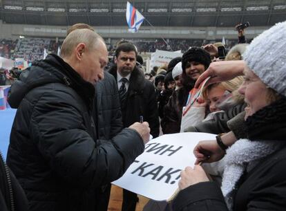 Putin da un aut&oacute;grafo durante un mitin electoral.