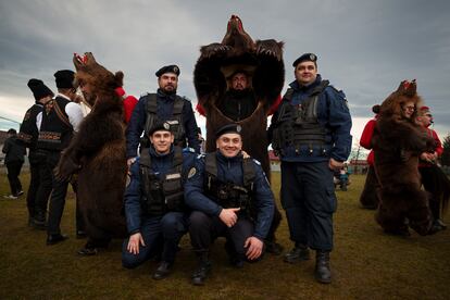 Romanian gendarmes pose for a photograph with members of the Sipoteni bear pack after watching their performance in Racova, northern Romania, Tuesday, Dec. 26, 2023. 