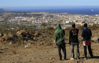 Varios inmigrantes contemplan la ciudad de Melilla desde el monte Gurugú. Un millar de ellos aguarda una oportunidad para saltar la valla.