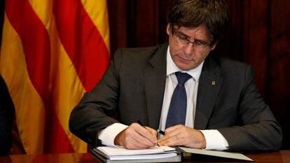 Catalan premier Carles Puigdemont signs the decree officializing the October 1 referendum.