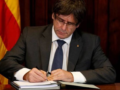 Catalan premier Carles Puigdemont signs the decree officializing the October 1 referendum.